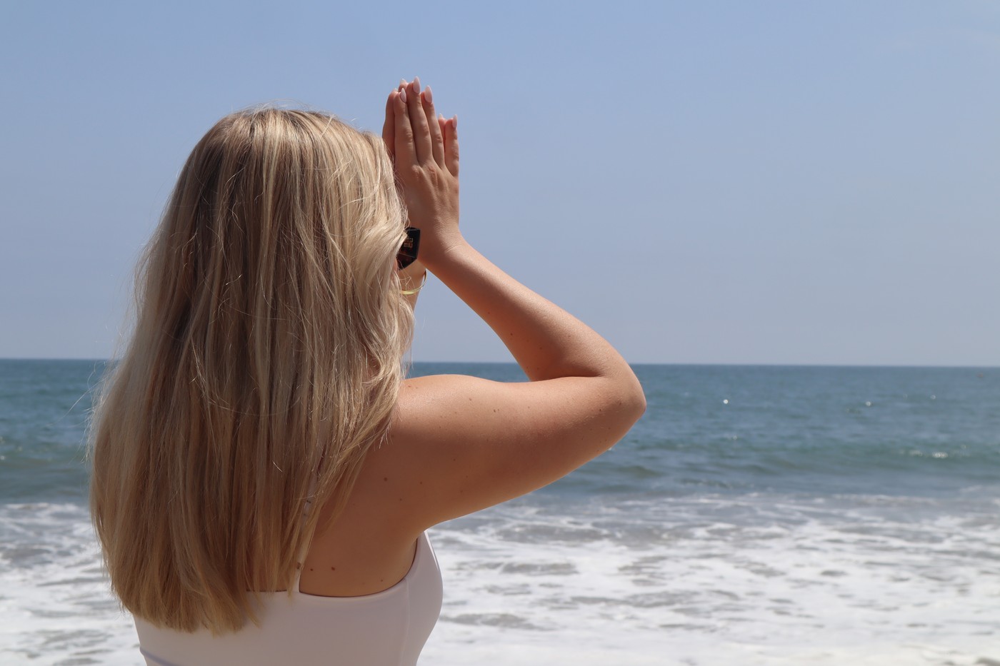 Hands raised by the ocean